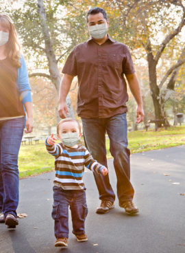 Happy Mixed Race Ethnic Family Walking In The Park Wearing Medical Face Mask