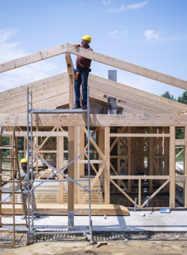 Construction Workers Working On Wooden Roof Of House.