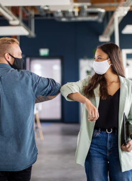 Business colleagues greeting with elbow in office