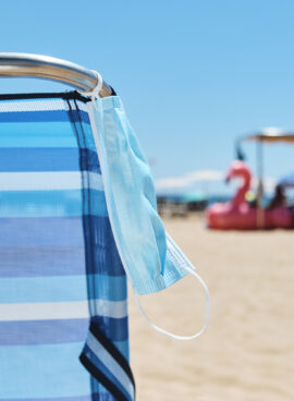 face mask hanging from a deck chair on the beach