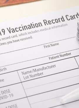 Covid-19 vaccination record card with vials and syringe.