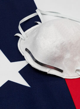 Texas state flag and N95 face mask. Concept of state and local government face covering mandate, order, requirement and social distancing during Covid-19 coronavirus pandemic