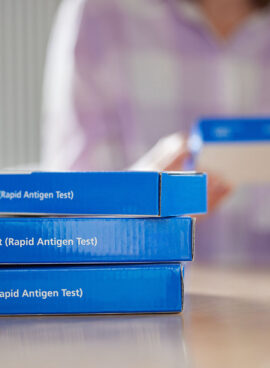 Close Up Of Woman At Home Reading Instructions On Supply Of Covid-19 Rapid Antigen Self-Testing Kits