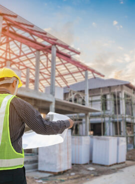 Professional engineer architect worker with protective helmet and blueprints paper at house building construction site