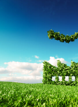 Eco friendly industry concept. 3d rendering of green factory icon on fresh spring meadow with blue sky in background.