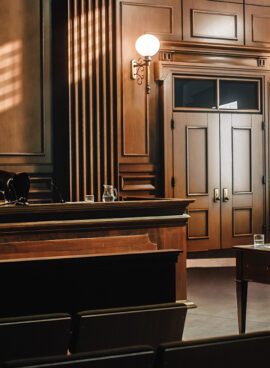 Empty American Style Courtroom. Supreme Court of Law and Justice Trial Stand. Courthouse Before Civil Case Hearing Starts. Grand Wooden Interior with Judge’s Bench, Defendant’s and Plaintiff’s Tables.