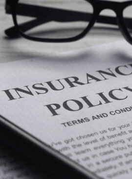 Selective focus of magnifying glass,glasses and Insurance Policy letter on a white wooden background.