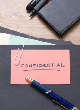 Black confidential files on a wooden desk with stationery