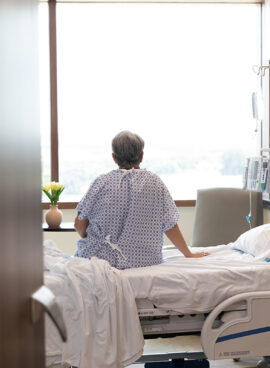 Unrecognizable female patient sits on her hospital bed