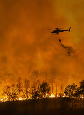 Fire fighting helicopter carry water bucket to extinguish the forest fire.